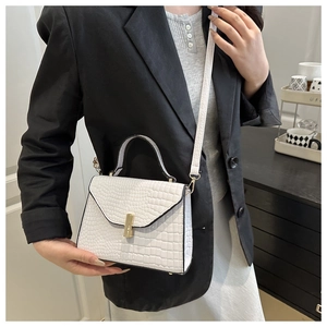 Détail d'un sac bandoulière blanc à motif crocodile avec boucle dorée et bandoulière