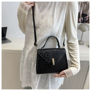 Détails de la texture cuir crocodile noir et boucle en métal doré sur le petit sac