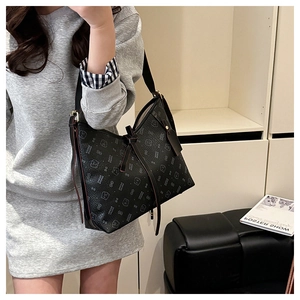 Detail of black large tote bag with bear print and long tassel side knot on strap
