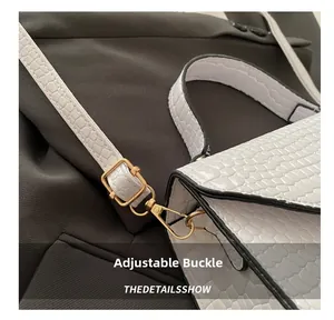 Détail de la boucle dorée ajustable et de la bandoulière en crocodile du sac blanc