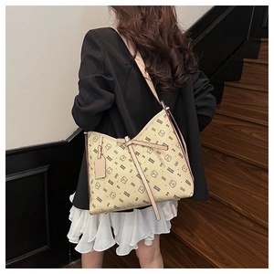 Detail of a beige tote bag with bear print and bow decoration on a model shoulder