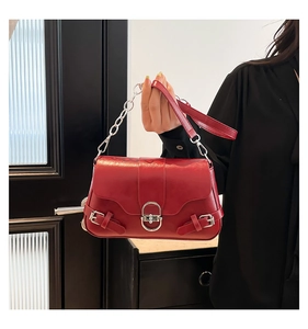 Détail du sac bandoulière en cuir rouge avec fermoir ovale argenté et chaîne métal