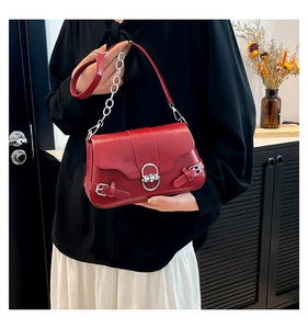 Détail d'un sac bandoulière en cuir rouge foncé avec fermoir ovale argenté et chaîne chic