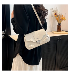 Détail du sac bandoulière minimaliste beige en similicuir avec fermoir rotatif en métal