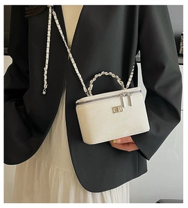 Detail of white snake print vanity bag with metal chain strap and twist lock on black suit