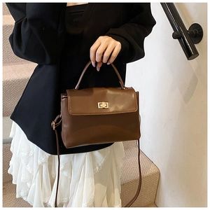 Detail of vintage brown soft leather bag with golden rectangular turn-lock on stone stairs