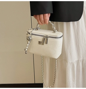 Close-up of white snake-embossed leather vanity case with metal woven handle and chain