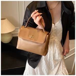 Detailed view of the tan leather handbag featuring a golden metallic twist lock closure