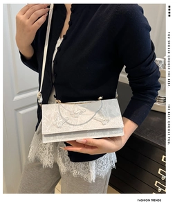 Detail of white lace handbag featuring 3D butterfly embroidery and gold metal handle