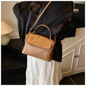 Caramel leather crossbody bag styled with a black blazer and white pleated skirt