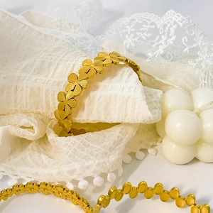 Detail of 18K gold plated stainless steel floral bracelet on elegant white lace background