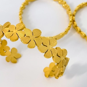 Macro detail of 18K gold-plated floral cuff bracelet with etched petal textures