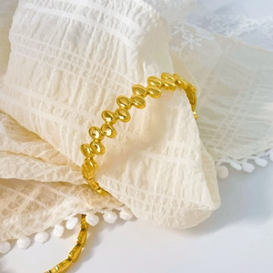Detail of 18K gold plated bean link bracelet with mirror polish on white lace fabric