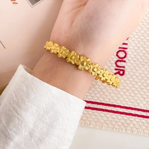 Detail of 18K gold plated daisy flower bracelet on wrist with textured metallic petals