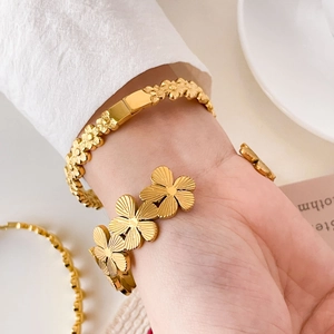 Detailed view of floral bracelets in 18K gold-plated titanium steel with brushed texture