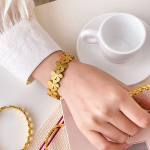 Detailed close-up of 18K gold-plated floral bracelet with engraved petal texture