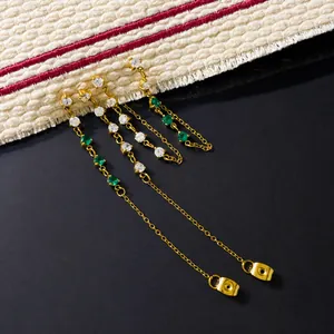 Détail de boucles d'oreilles à pampilles dorées avec zircon vert et plaqué or 18K