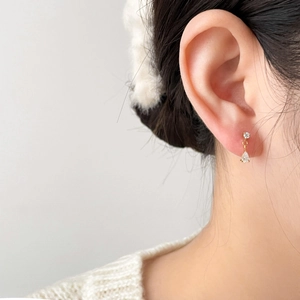 Détail des boucles d'oreilles dorées avec zircon goutte sur l'oreille du mannequin