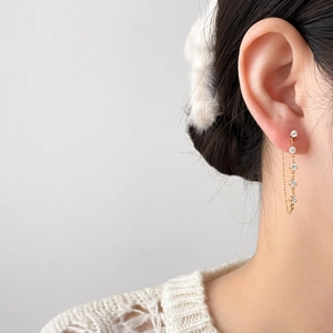 Détail de boucles d'oreilles pendantes dorées avec zircons fins et motifs floraux