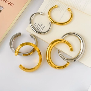 Close-up of gold and silver minimalist chunky C-shape open bangles in layered style