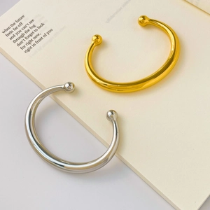 Detailed view of minimalist gold and silver cuff bangles on an open book background