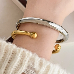 Detail of stacked gold and silver bangles with spherical accents on a female model wrist