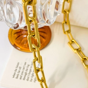 Macro detail of high-shine gold-plated rectangular link chain in industrial style