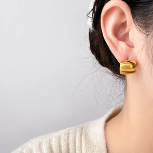 Close-up of golden geometric C-shaped hoop earring on model with elegant glossy finish