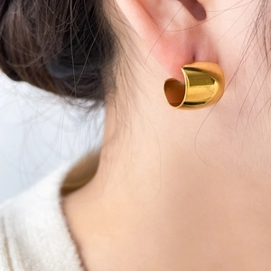 Detail shot of a model wearing the chunky golden wave geometry C-shape stud earrings