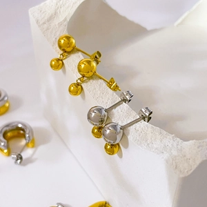 Detail of high-polish gold and silver double steel ball stud earrings on stone