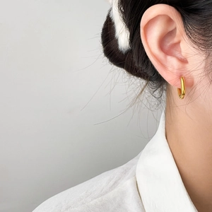Minimalist geometric gold hoop earrings with polished finish shown on model