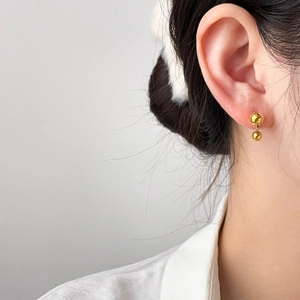 Close-up of minimalist gold double ball drop earrings on model with polished finish