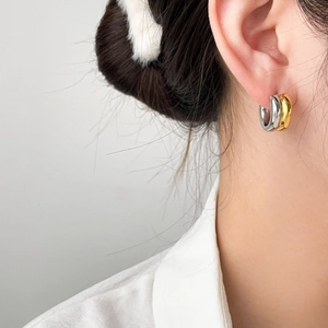 Close-up of model wearing two-tone gold and silver thick C-shape hoop earrings