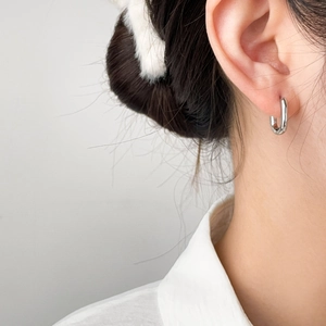 Close-up of minimalist silver geometric earring worn on model, sleek polished steel finish