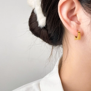 Minimalist rectangular gold earring with brushed matte finish on female model ear