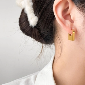 Close-up of minimalist gold U-shape titanium steel earrings worn by a female model