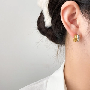 Two-tone chunky oval hoop earrings in gold and silver finish on a female model