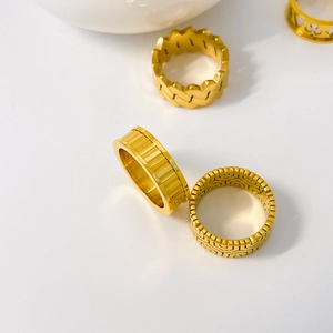 Detail view of four 18K gold plated titanium steel rings with gear and woven patterns