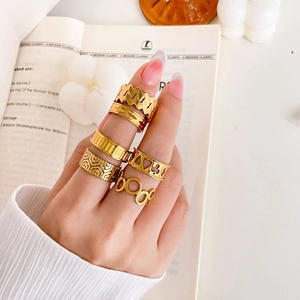 Close-up of 6-piece set of gold hollow chain and gear engraved rings on fingers