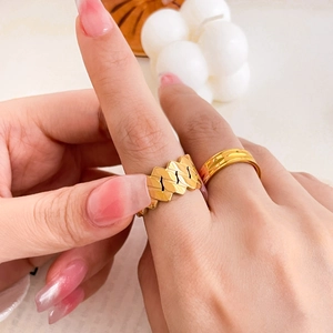 Detail of 18K gold plated titanium ring set with hollow chain and textured gear design