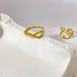 Détail d'une bague multicouche croisée plaquée or 18 carats sur un support en plâtre