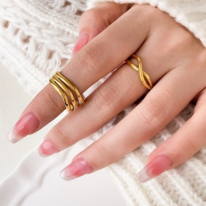 Détail d'une bague multicouche en acier plaqué or 18 carats portée sur une main avec manucure