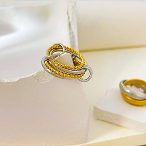 Detail of layered titanium steel rings with twisted rope and beaded textures in gold and silver