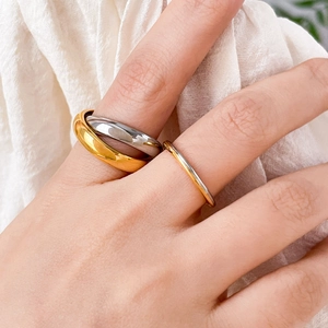 Detail of layered gold and silver stainless steel rings worn on fingers
