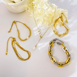 Multi-layer gold and silver mixed chain bracelet set with freshwater pearls on white surface