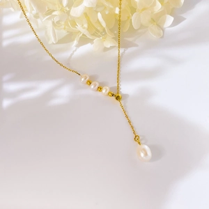 Close-up of a Y-shaped gold necklace featuring four round pearls and a drop pearl pendant