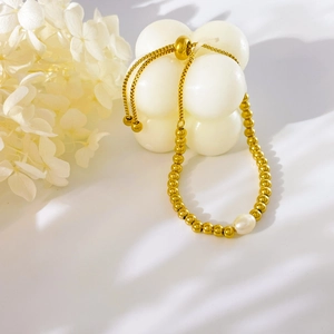 Detail of adjustable gold bead bracelet featuring a single white freshwater pearl charm