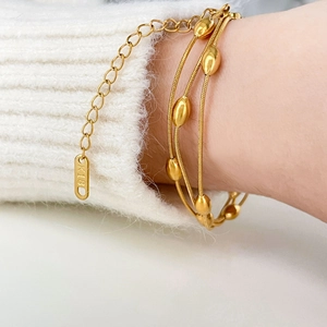 Close-up of triple-layer gold snake chain bracelet featuring oval beads and K18 hallmark