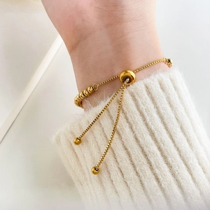 Detailed shot of golden box chain bracelet with adjustable bead slider on a white wrist