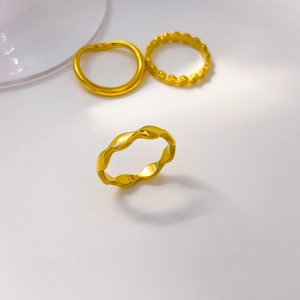Detailed view of three 18K gold plated wavy and geometric textured titanium steel rings